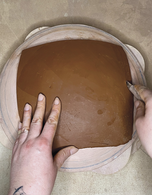 2 Place a slab onto a bisque hump mold. Compress and smooth the slab.
